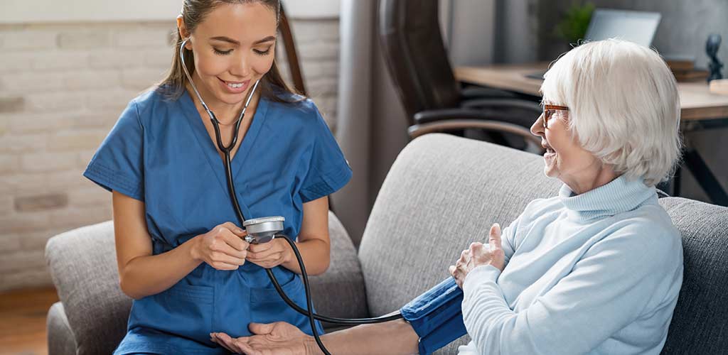 Home Health Aide checks blood pressure of senior at home