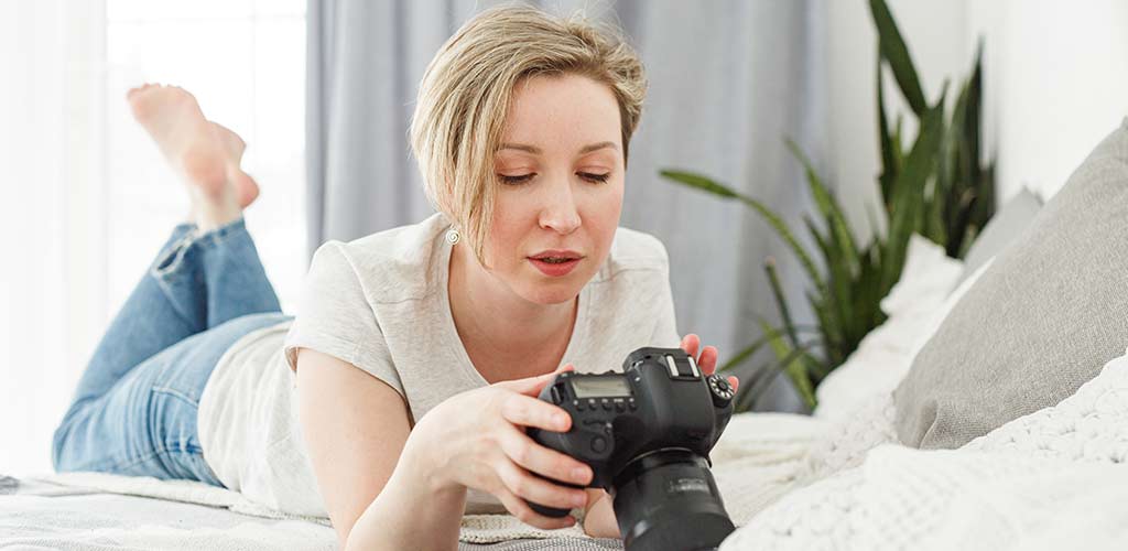 Woman lying on bed with camera in hand